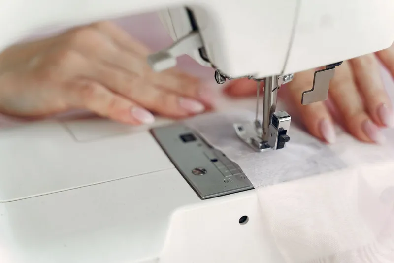 Manos guiando una tela en la máquina de coser