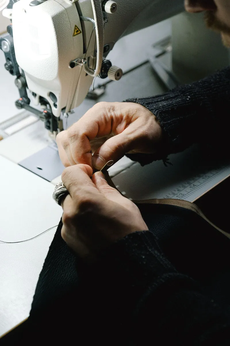 Manos sujetando una tela bajo la máquina de coser